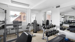 Une salle de sport équipée de divers appareils d’exercice, d’un banc et d’haltères.