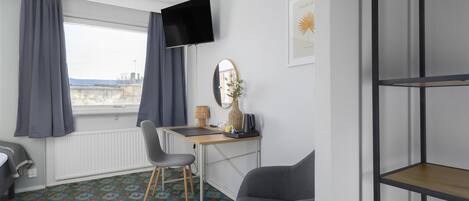 Quarto moderno com escrivaninha, cadeira e televisão.