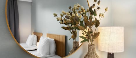 A hotel room with a bed, a mirror, and a lamp.
