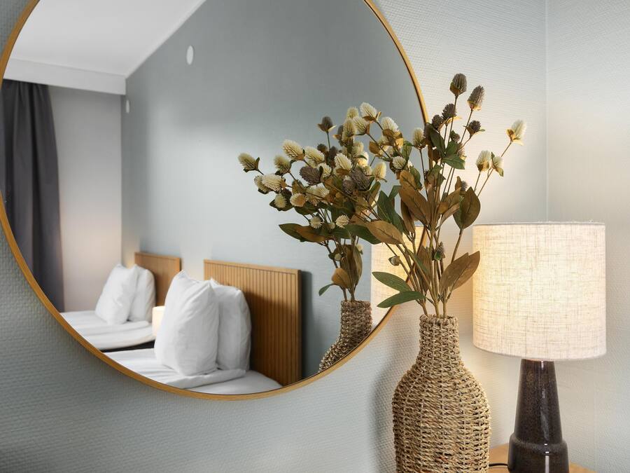 Ett hotellrum med en säng, en spegel och en lampa.