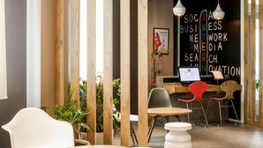 Ein moderner Arbeitsplatz mit Holzwänden, weißen und roten Stühlen und einem Schreibtisch mit einem Computer.