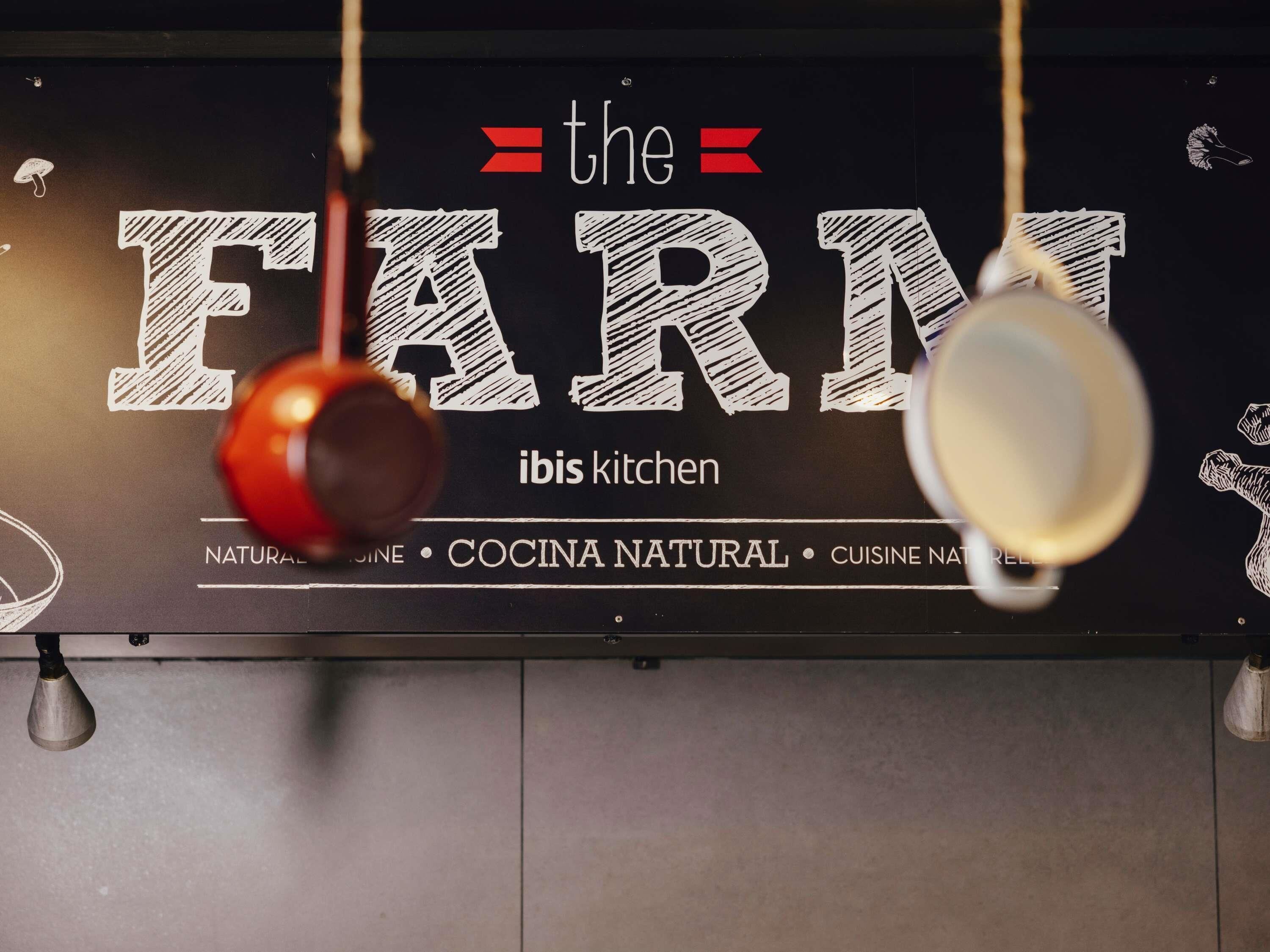 Een keukenhoek met een bord waarop 'the FARM' en 'ibis kitchen' staat, wat wijst op een focus op natuurlijke keuken.
