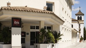 Ein Hotel mit einem gut sichtbaren 'ibis'-Schild, einem Ziegeldach und traditioneller Architektur.