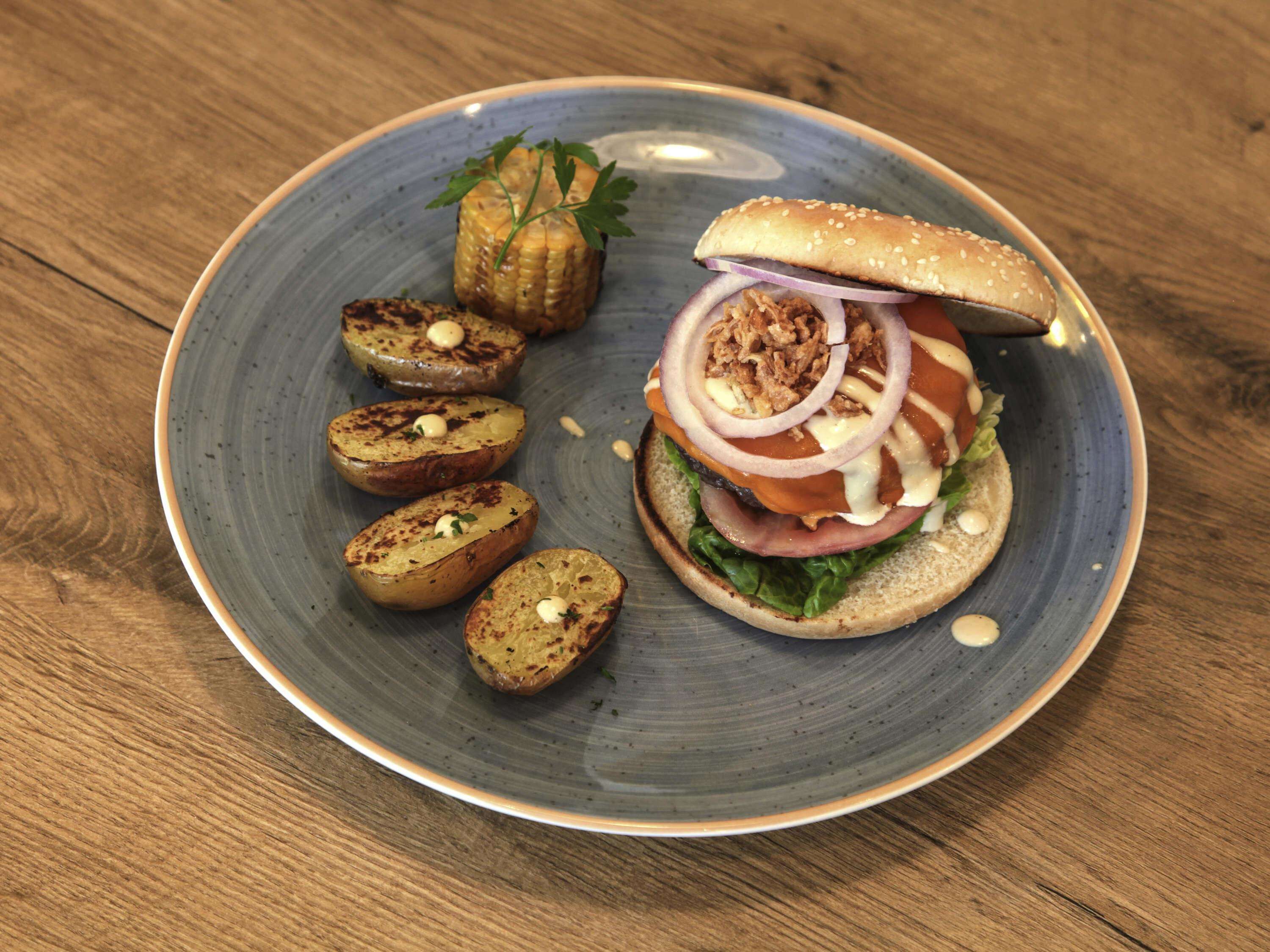 Un plato con un sándwich, patatas asadas y una guarnición.