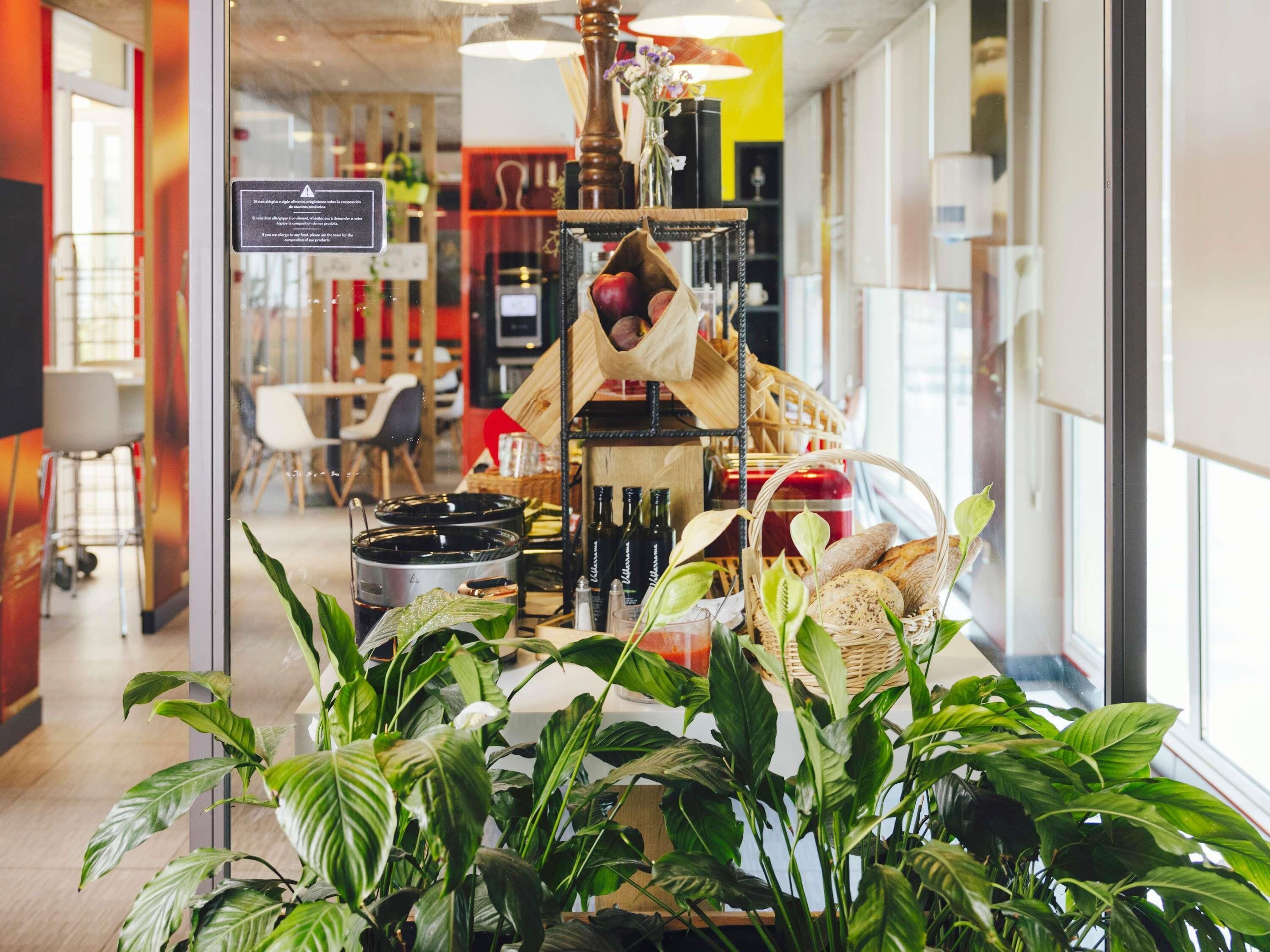 Interior de una cafetería con un mostrador que exhibe pan, bollería y una máquina de café.