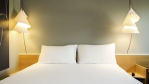 Ein ordentlich bezogenes Bett mit weißen Leinen und zwei Nachttischlampen.