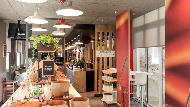Eine Bäckertheke mit Brot, Gebäck und Getränken, eine Kaffeemaschine und ein Schild, das auf ein Restaurant hinweist.