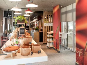 A bakery counter with bread, pastries, and drinks, a coffee machine, and a sign indicating a restaurant.