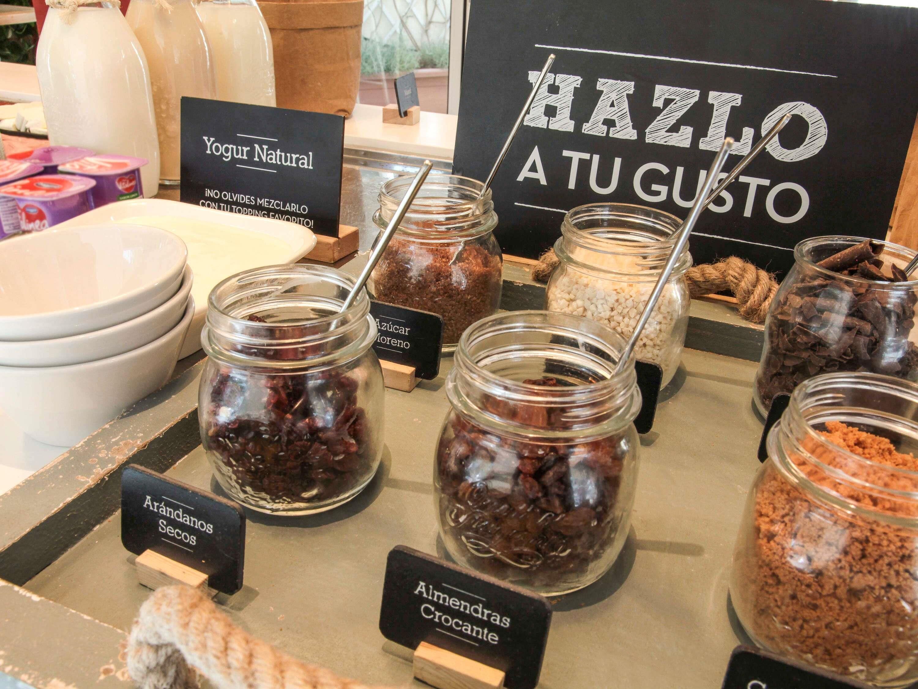 Une sélection de produits alimentaires en pots, chacun étant muni d’une étiquette, une pancarte indiquant « Faites-le à votre goût » et une autre pancarte indiquant « Yaourt nature ».