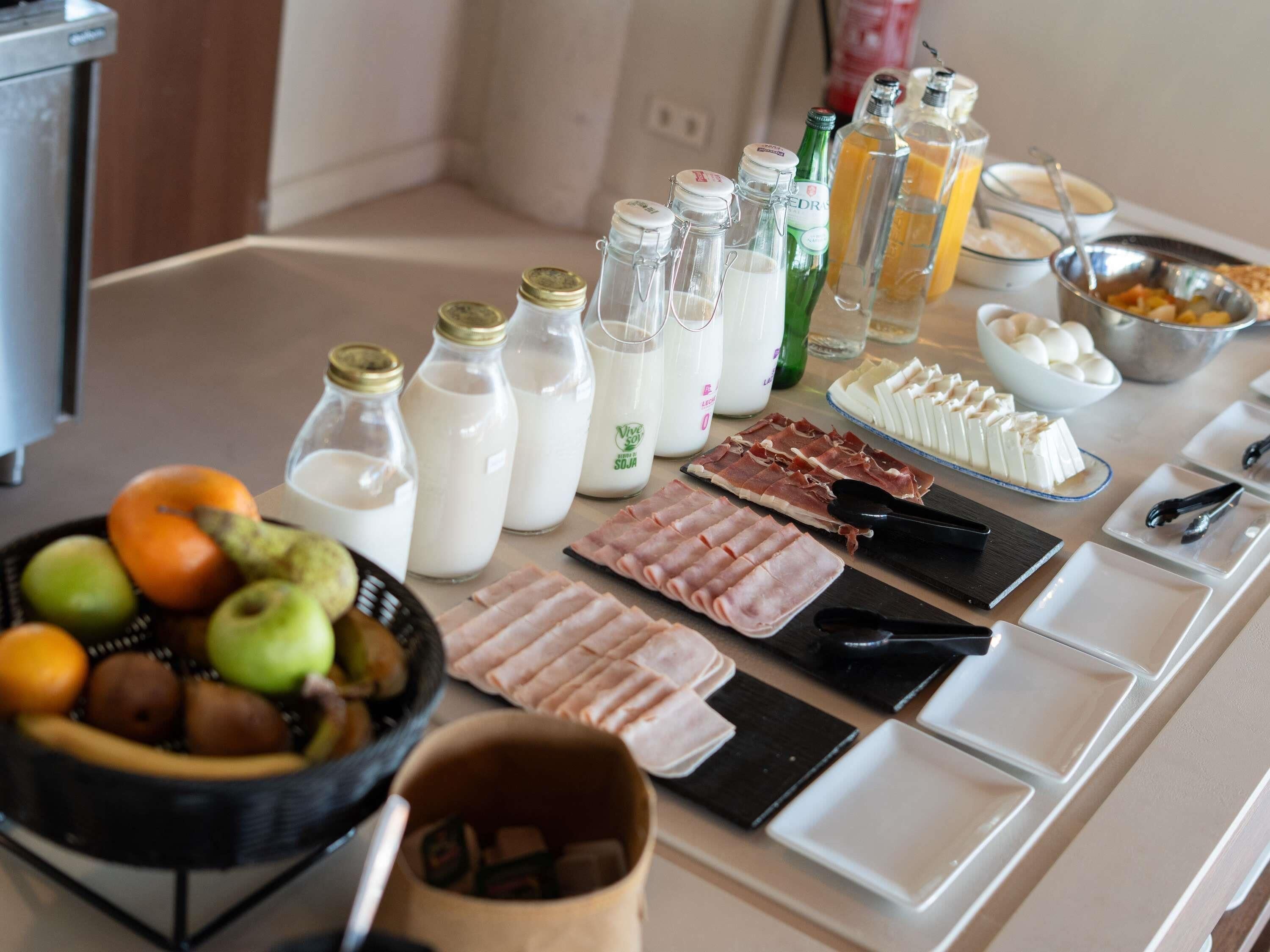 A buffet table with various food items, including fruits, dairy products, and meats.