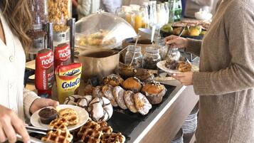 Een buffet met diverse etenswaren, waaronder wafels, muffins en gebak.