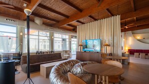 Un interior moderno con techo de madera, ventanas amplias, televisor de pantalla plana y una variedad de zonas de estar.