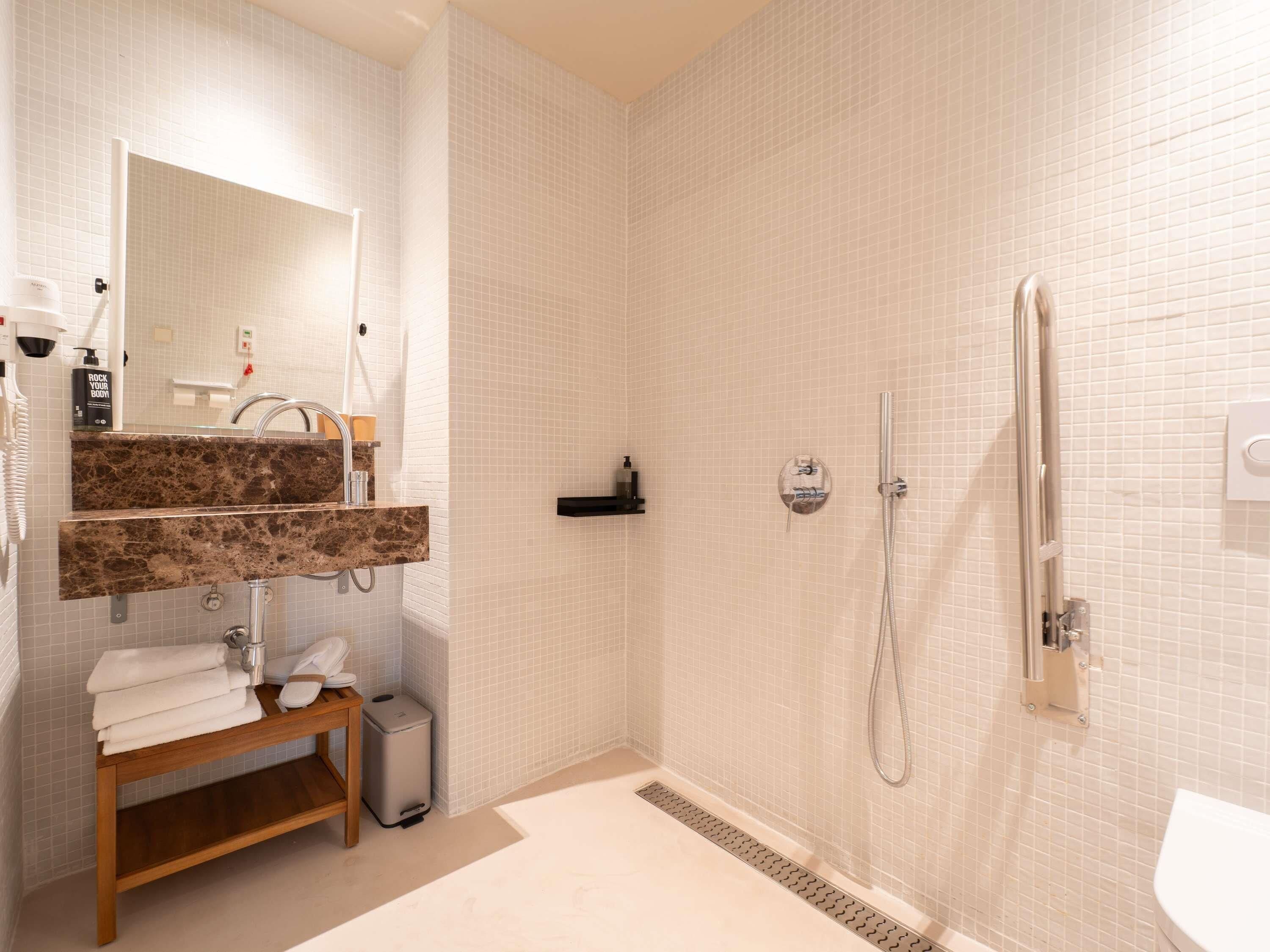 Et moderne badeværelse med en marmorvask, et spejl, brusehoved og toilet.