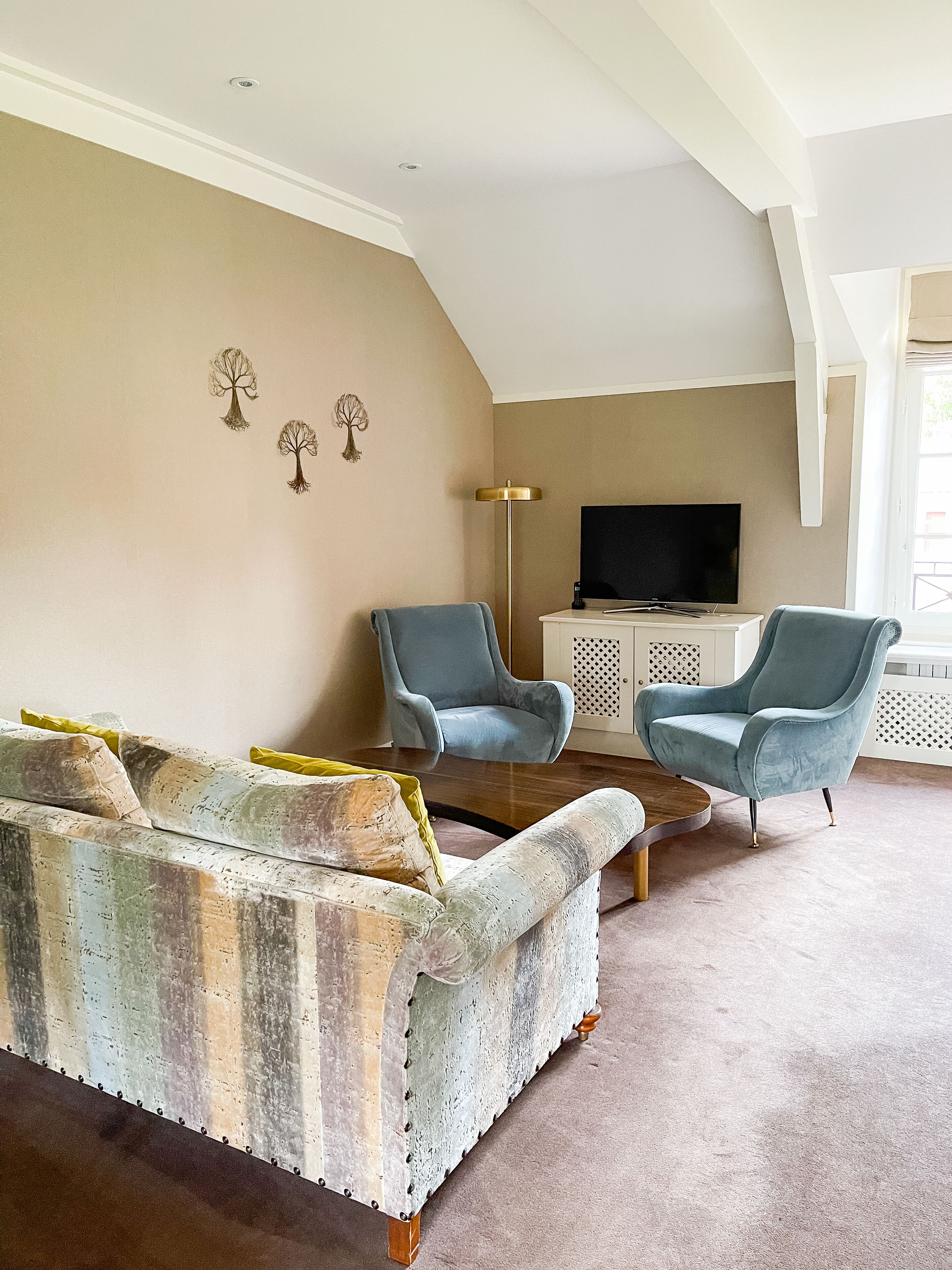 A living room with a sofa, two armchairs, a coffee table, and a TV.