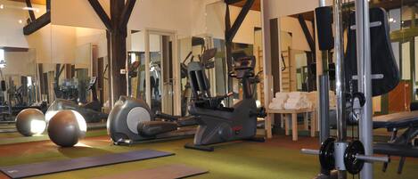 A gym with exercise equipment, mirrors, and a green carpet.