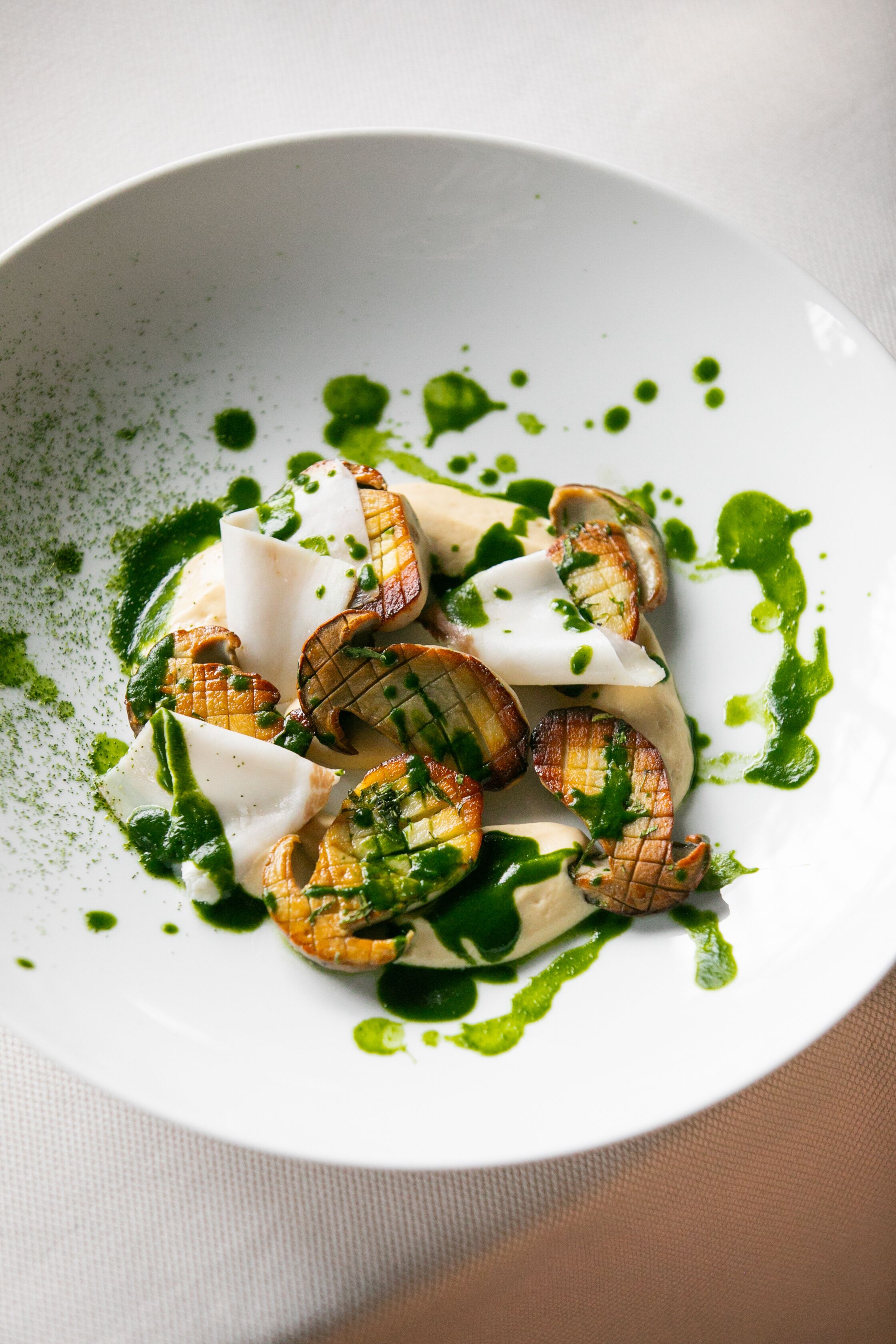 A white plate with grilled vegetables and a green sauce.
