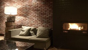 Un cuarto acogedor con pared de ladrillo, un sofá, una mesa con lámpara y una chimenea.
