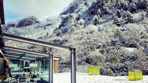 Una habitación moderna con paredes de vidrio y vistas a montañas nevadas.