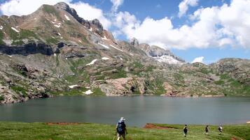 Un paisaje montañoso con un lago, excursionistas y terreno rocoso.