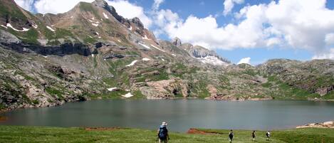 A mountainous landscape with a lake, hikers, and rocky terrain.