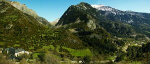A mountainous landscape with a large building surrounded by greenery and a snow-capped peak in the background. - Hotel Santa Cristina (Canfranc)