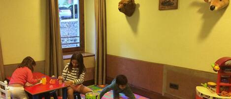 A room with a play area, a window with curtains, and a wall-mounted animal head.