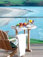 A dining table with a view of the sea, a chair, and a towel.