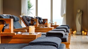 Une salle de spa équipée de plusieurs fauteuils de massage, de bougies et d’une statue.