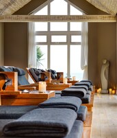 A spa room with multiple massage chairs, candles, and a statue.