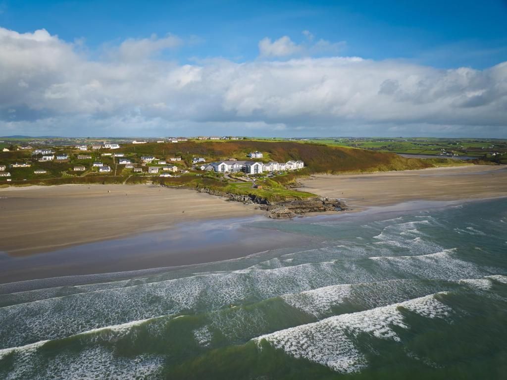 A coastal property with a beach, a rocky outcrop, and a cluster of white buildings.