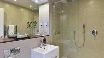 A modern bathroom with a glass-enclosed shower, a white sink, and a mirror above it.