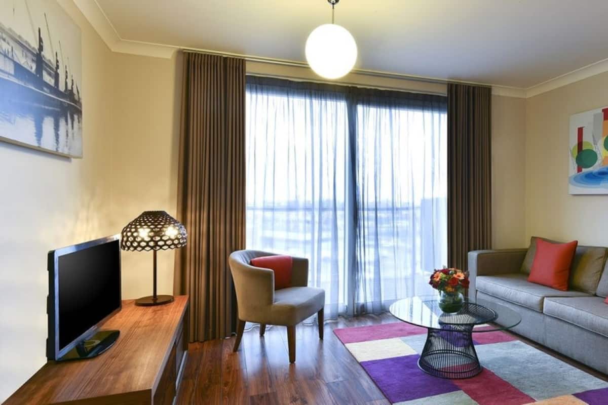 A modern living room with a flat-screen TV, a chair, a sofa, a coffee table, and a painting on the wall.