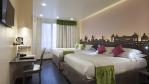 Habitación de hotel con dos camas, un escritorio, una silla, un televisor de pantalla plana y un mural con vistas a la ciudad.