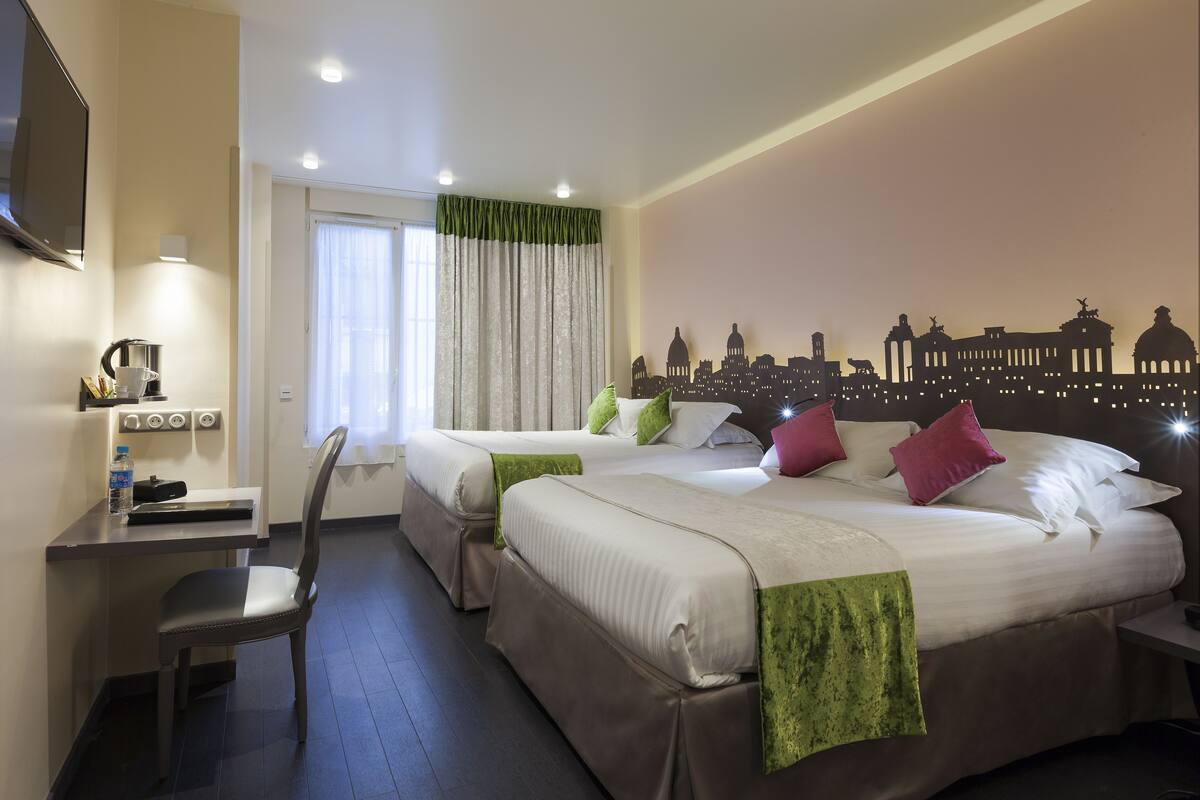 Habitación de hotel con dos camas, un escritorio, una silla, un televisor de pantalla plana y un mural con vistas a la ciudad.