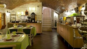 Una cocina rústica con techo de ladrillo visto, armarios de madera y un comedor con manteles verdes.