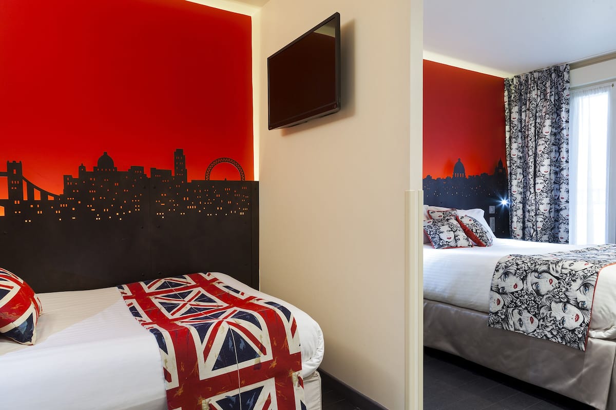 Una habitación de hotel con dos camas, una con una colcha temática de la Union Jack y la otra con un edredón estampado.