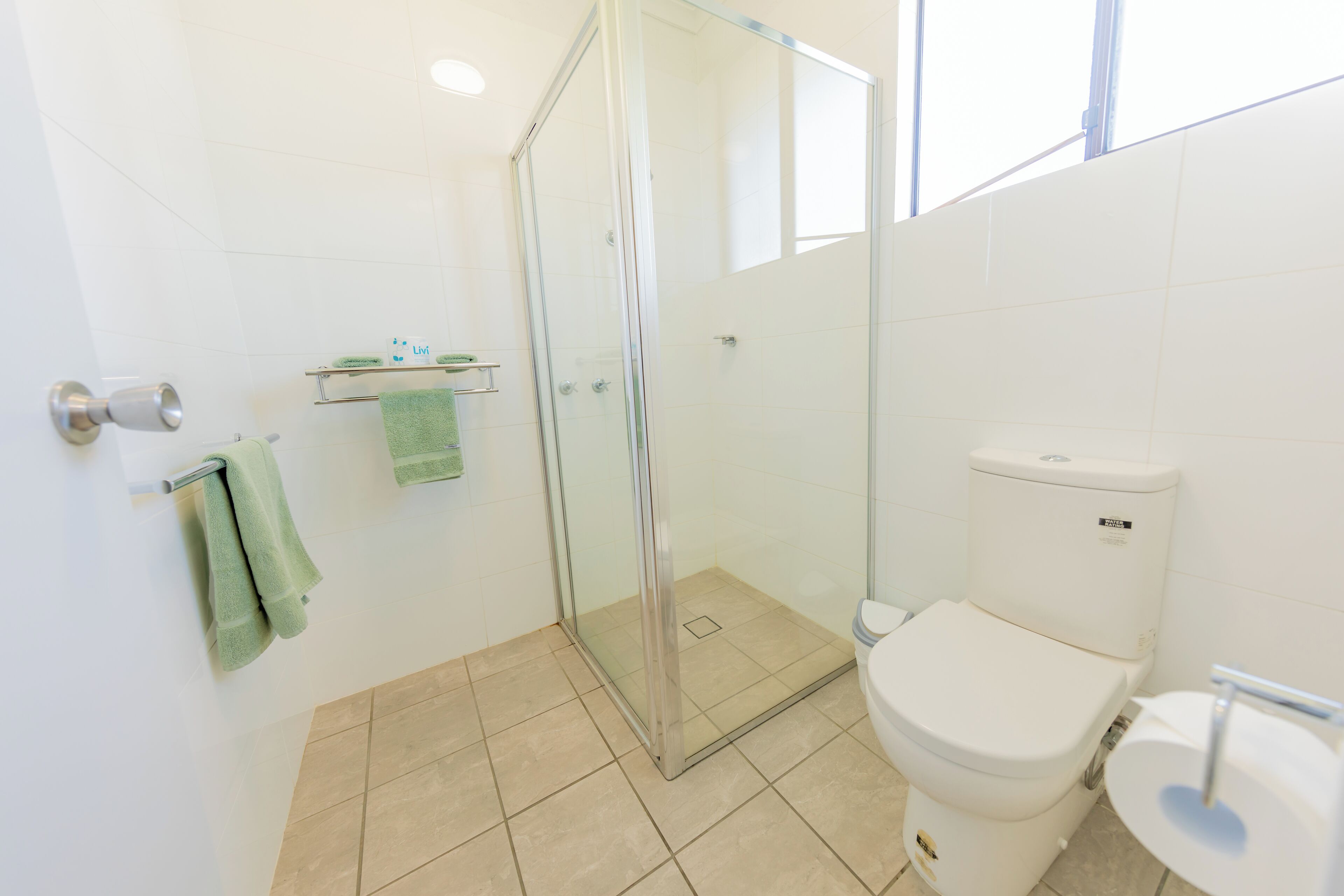 Un baño moderno con ducha corredera de vidrio, inodoro y lavabo.