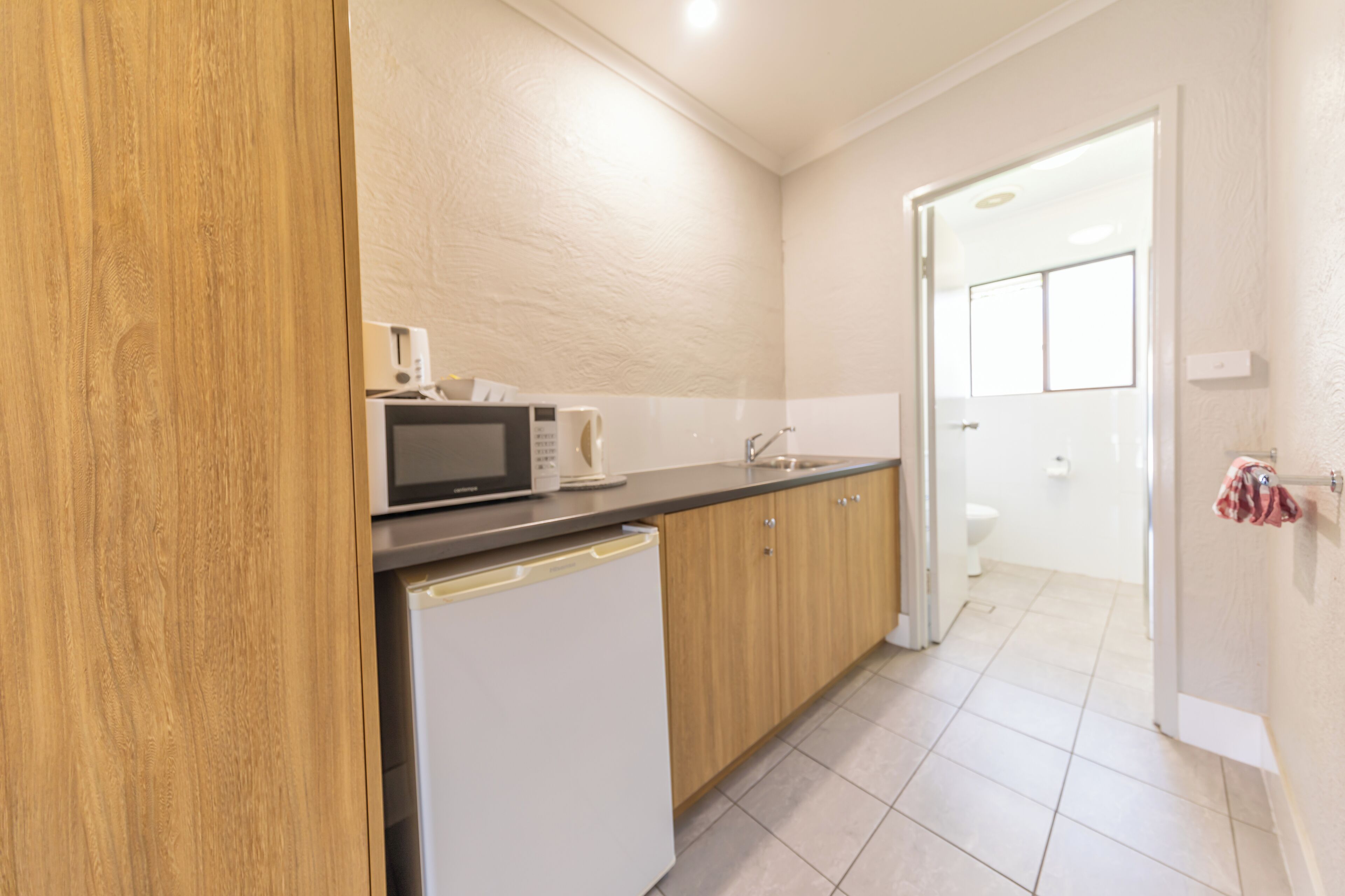 A compact kitchen with a microwave, coffee maker, and a sink.