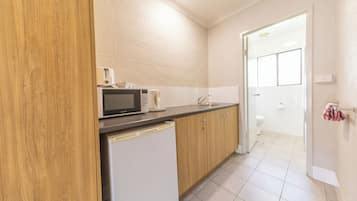 A compact kitchen with a microwave, coffee maker, and a sink.