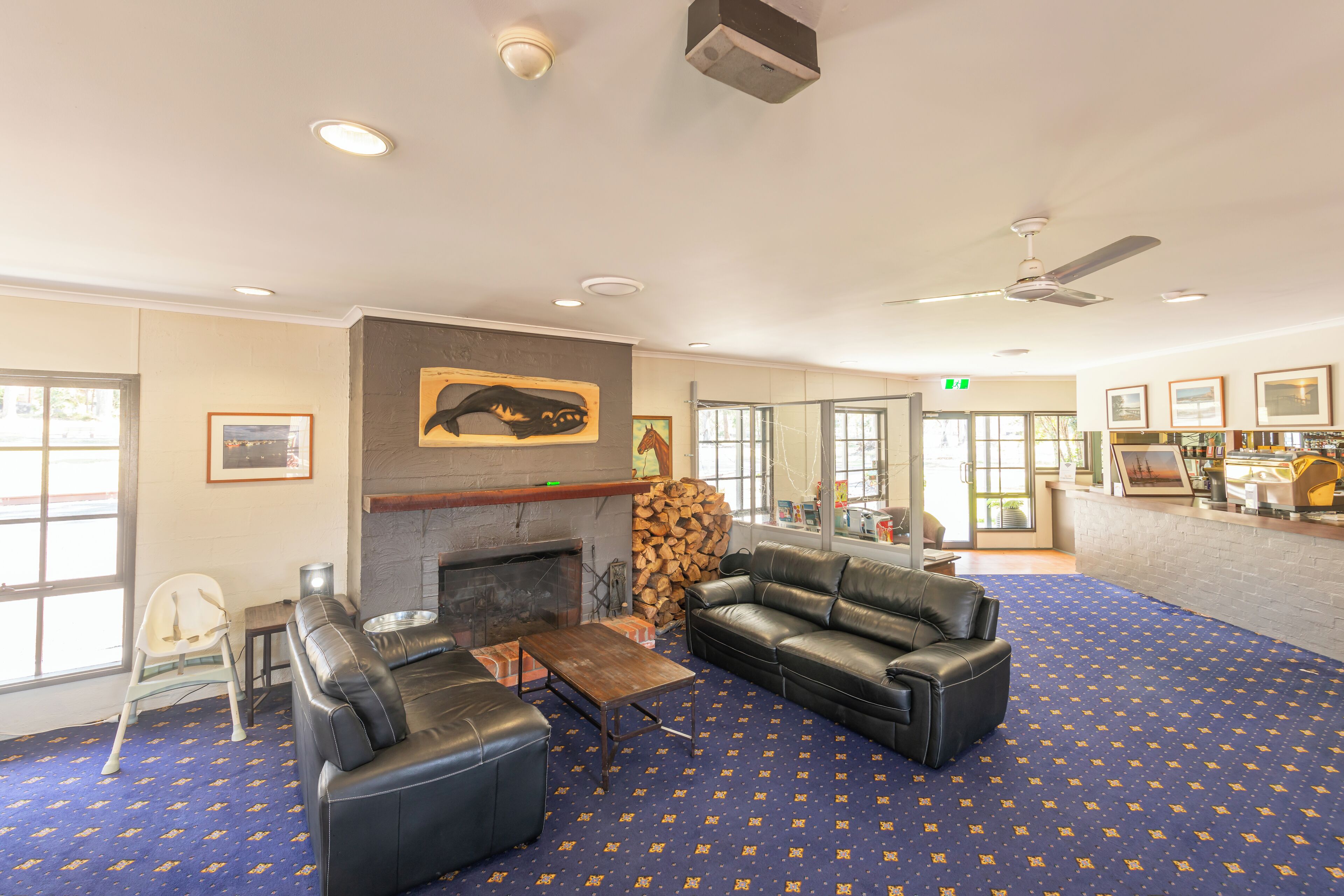 A spacious lobby with a fireplace, leather sofas, a coffee table, and a patterned carpet.