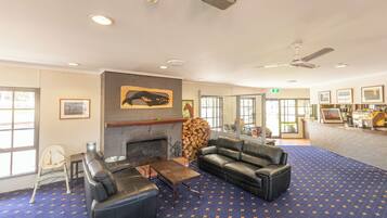 A spacious lobby with a fireplace, leather sofas, a coffee table, and a patterned carpet.