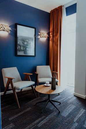 Relax in this stylish room with a large window, two armchairs, and a side table.