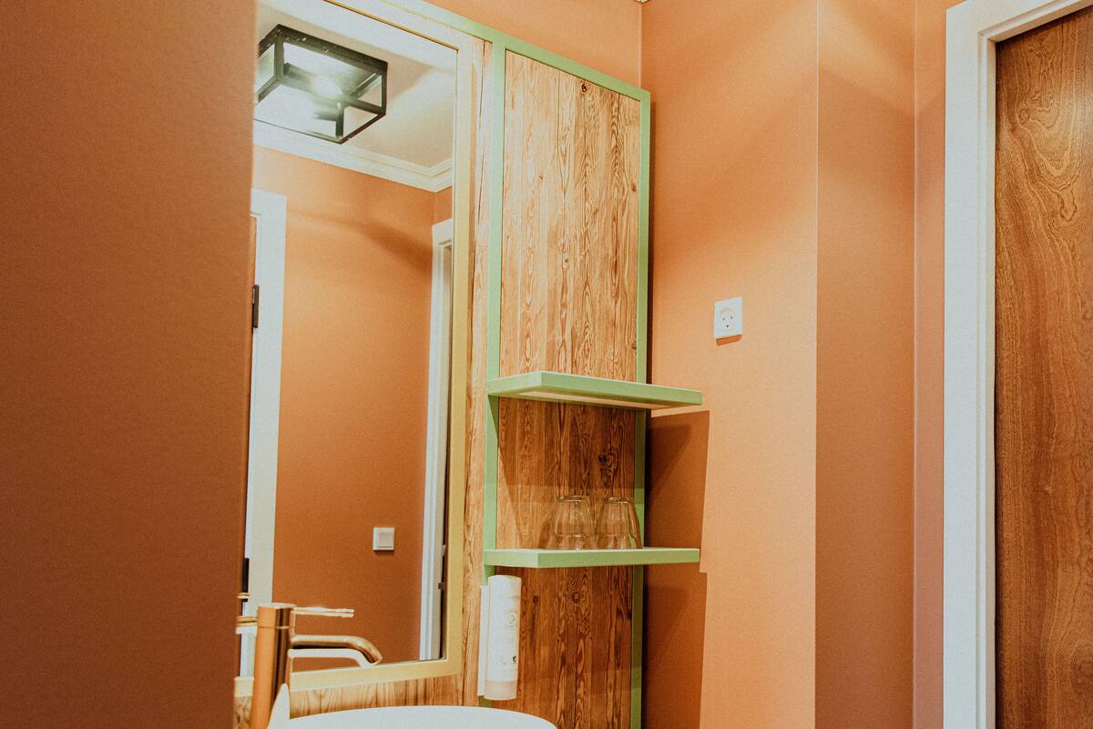 Une salle de bain avec un lavabo rond, un miroir et des étagères en bois.