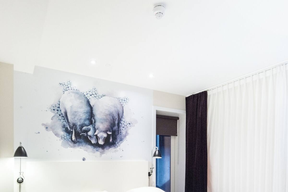 Une chambre à coucher avec un lit double, une table de chevet, une lampe et un tableau mural.