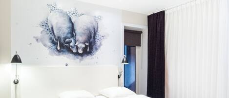 Un dormitorio con una cama doble, una mesita de noche, una lámpara y un cuadro en la pared.