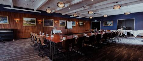 A conference room with a long table, chairs, and framed pictures on the walls.
