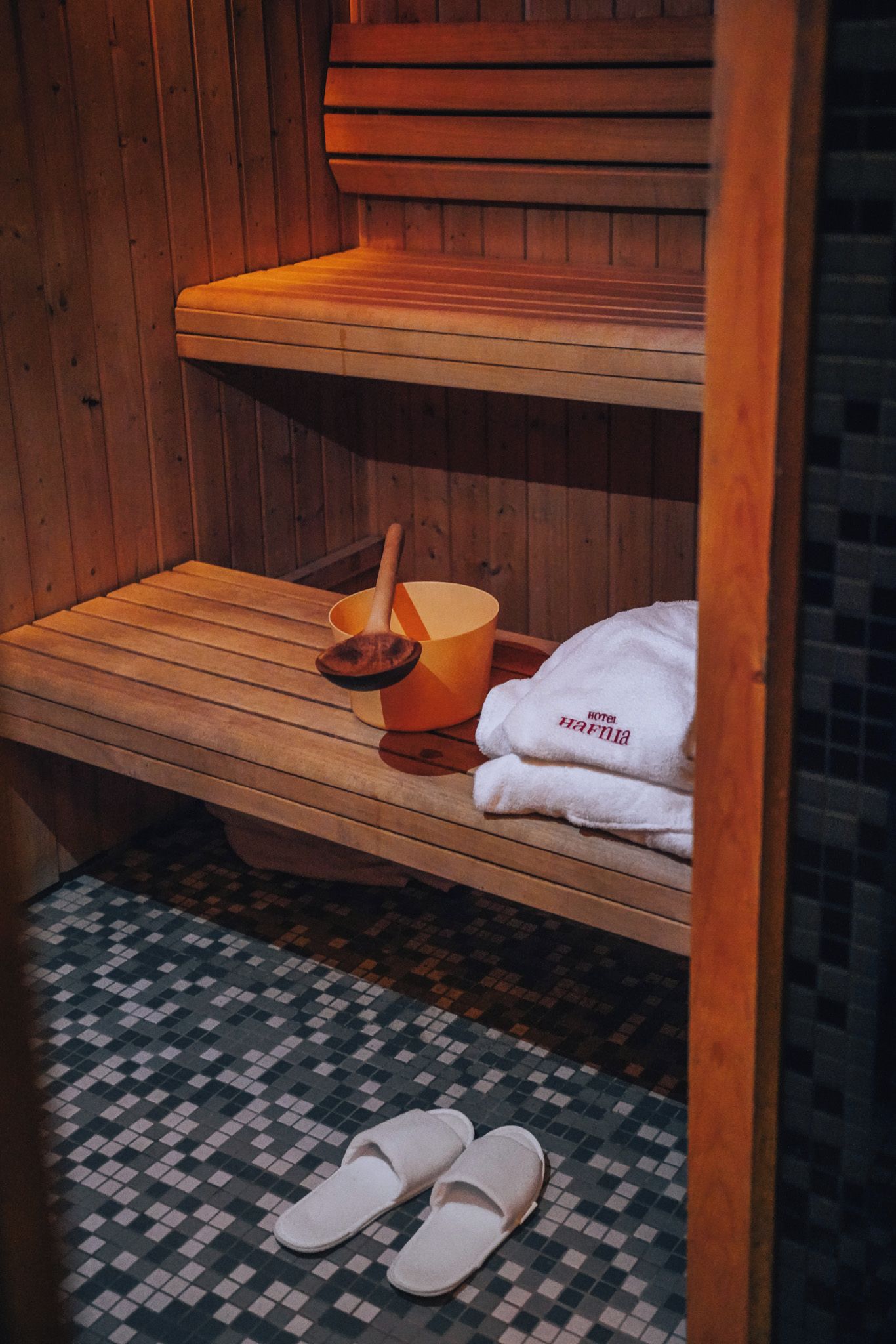 Un banc de sauna de fusta amb una tovallola i una cullera de fusta.