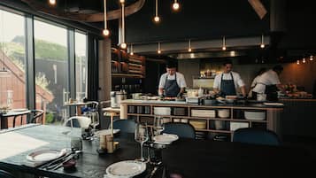 Een restaurantinterieur met een eethoek, keuken en grote ramen.