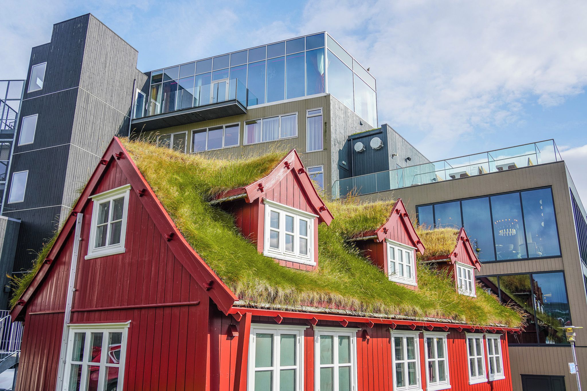 A red building with a grass roof and multiple windows.