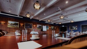 A conference room with a long wooden table, multiple chairs, and framed artwork on the walls.